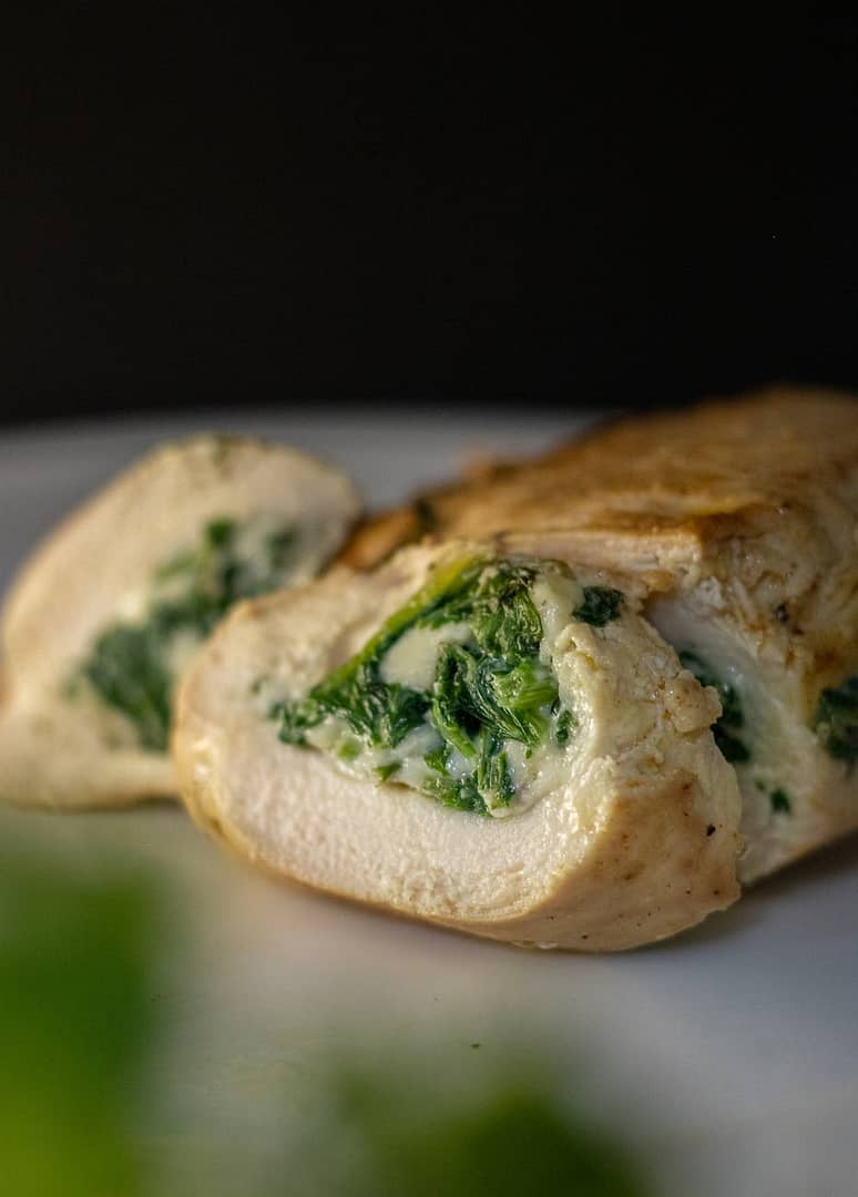 close up of a chicken breast roulade with spinach filling